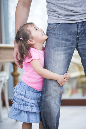 Side view of girl hugging father's leg in houseの写真素材