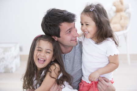 Happy father with daughters spending quality time together at homeの写真素材