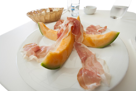 Melon slices with meat served on plateの写真素材