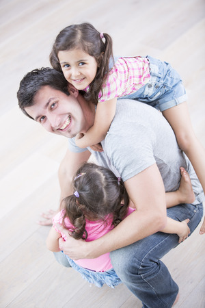 High angle portrait of playful father carrying girls at homeの写真素材