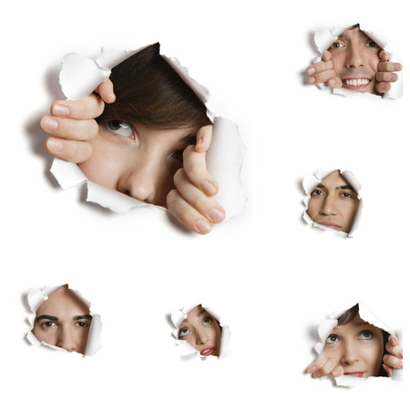 Multiethnic people looking through ripped paper holesの写真素材