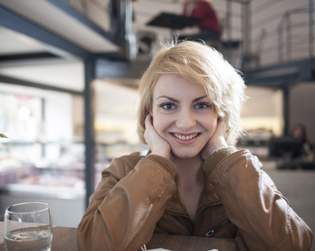 Portrait of beautiful young woman smiling in cafeの写真素材