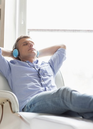 Relaxed Middle-aged man listening to music at homeの写真素材