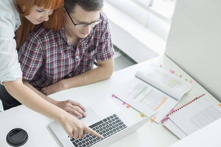 Business couple using laptop in creative officeの写真素材