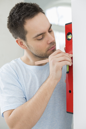 Mid-adult man marking on wall with levelの写真素材