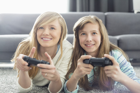 Sisters playing video games in living roomの写真素材