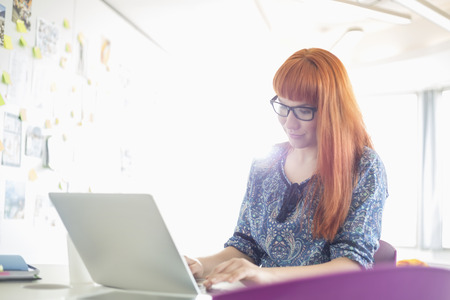 Businesswoman using laptop in creative officeの写真素材