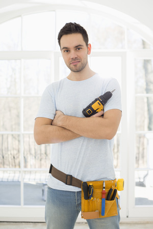 Portrait of confident man with hand drill in new houseの写真素材