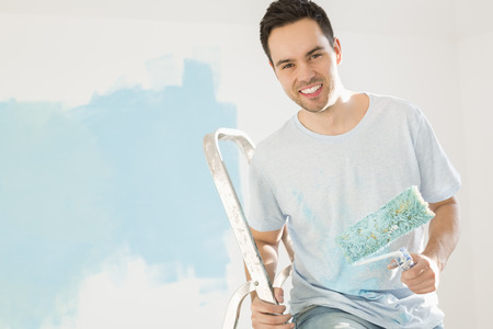 Portrait of happy man painting his new houseの写真素材