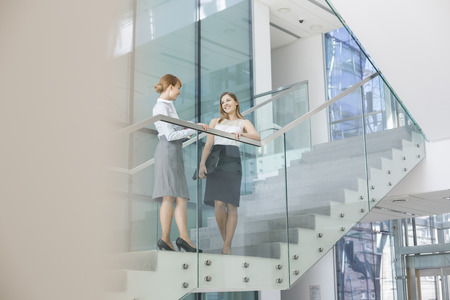 Businesswomen conversing on steps in officeの写真素材