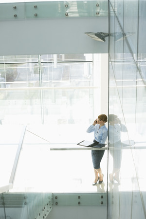 Businesswoman using cell phone in officeの写真素材
