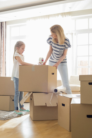 Mother and daughter packing cardboard boxes at homeの写真素材