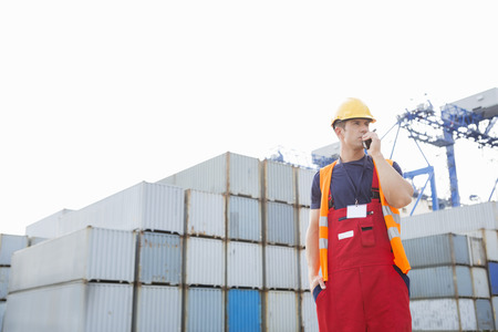 Male worker using walkie-talkie in shipping yard
