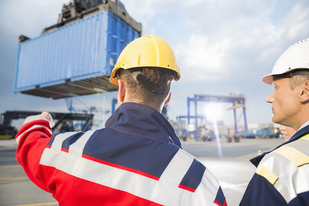 Rear view of male workers discussing in shipping yard