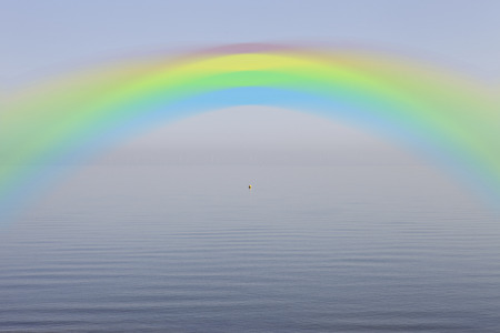 Rainbow over calm lakeの写真素材