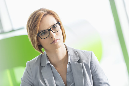 Young businesswoman looking away in officeの写真素材