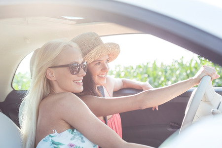 Happy female friends enjoying in car on sunny dayの写真素材