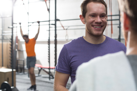 Happy man talking to male friend in crossfit gym