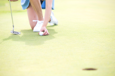 Low section of woman placing ball at golf courseの写真素材