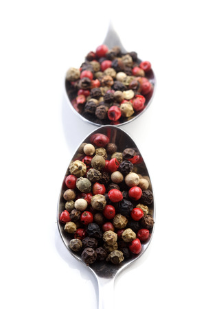 Pepper grains on spoon on white backgroundの写真素材
