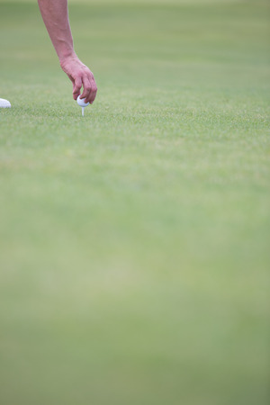 Hand placing ball on golf teeの写真素材
