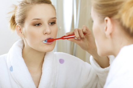 Woman in bathroom brushing teeth