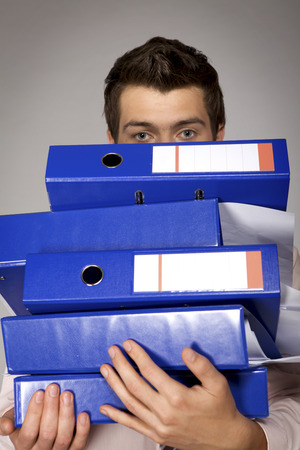 Young caucasian businessman holding a stack of bindersの写真素材
