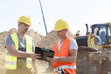 Engineers reading clipboard at construction site against clear skyの写真素材