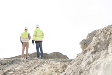 Rear view of supervisors standing at construction site against clear skyの写真素材