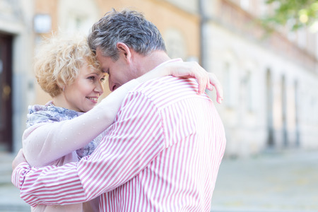 Happy middle-aged couple embracing in cityの写真素材
