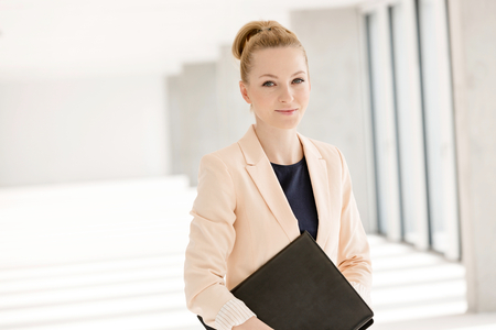 Portrait of confident young businesswoman with file in new officeの写真素材