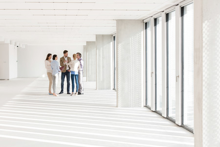 Full length of business people discussing in empty officeの写真素材