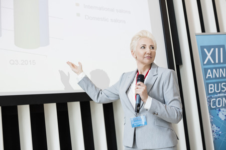 Businesswoman explaining strategy on projection screen at convention center