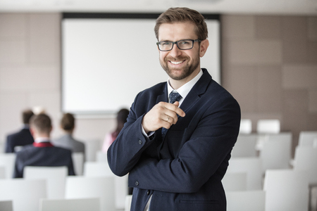 Portrait of happy businessman standing in seminar hallの写真素材