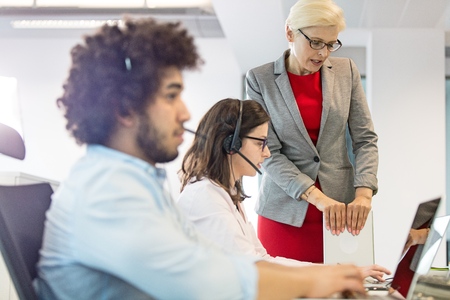 Mature businesswoman assisting female operator with colleague in foreground at office
