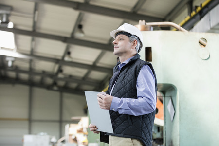 Side view of male supervisor holding clipboard in metal industry