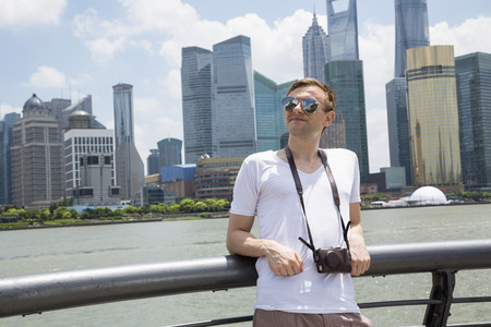 Thoughtful man leaning on railing against Shanghai World Financial Centerの写真素材