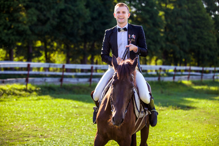 Portrait of happy man riding horse on fieldの写真素材