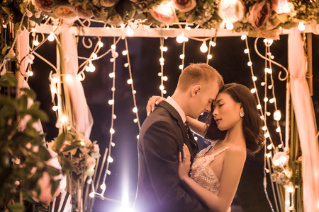 Side view of romantic couple embracing in illuminated gazebo at nightの写真素材
