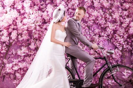 Wedding couple looking at each other against wall covered with pink flowersの写真素材