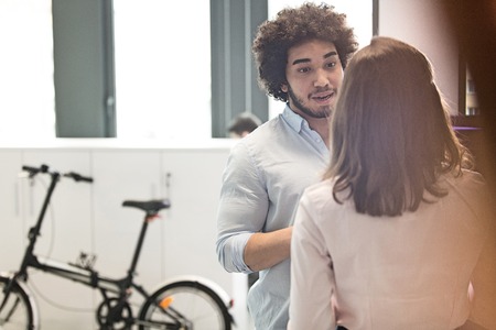 Young businessman talking with female colleague in officeの写真素材