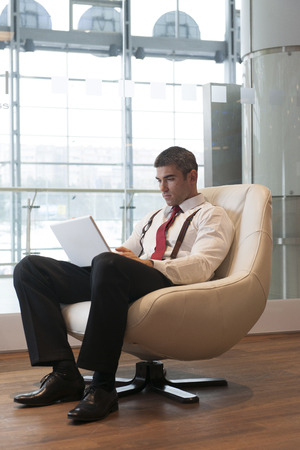 Businessman in arm chair working on laptopの写真素材