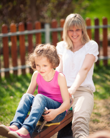 Mother and daughter ride seesaw togetherの写真素材
