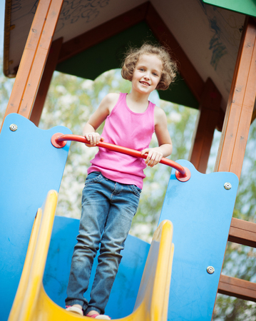 Young girl standing at top of slide in playgroundの写真素材