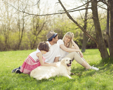 Family sitting in park with dog