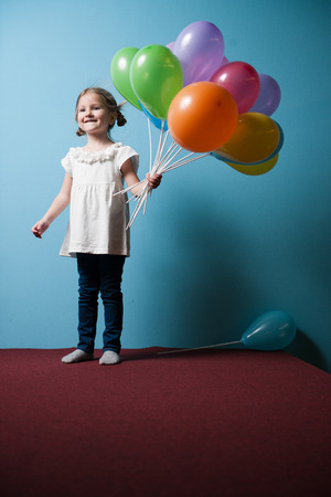 Young girl holds bunch of colorful balloonsの写真素材