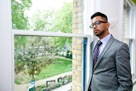 Portrait of Indian Businessman wearing glasses standing by the windowの写真素材