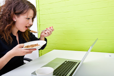 Close up of woman eating at her deskの写真素材