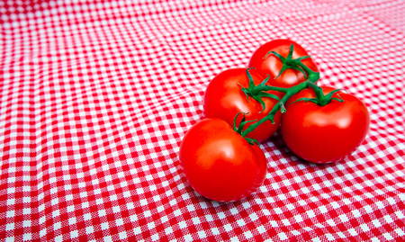 Red Vine tomatoes against red and white chequered clothの写真素材