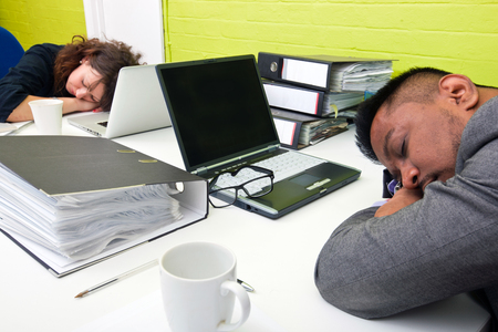 Colleagues asleep at their respective deskの写真素材